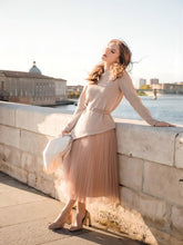 A lady wears a sweater and a skirt.